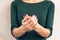 Woman in green T-shirt shows a hands with a maroon manicure