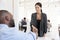 Woman greeting a black businessman at an office meeting