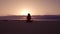 Woman greeting the sun with a yoga pose on the beach in the morning