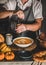 Woman in grey apron putting pepper to pumpkin cream soup