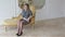 A woman in grey business dress is sitting on a golden vintage couch.