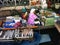 A woman grills fish in the kitchen of a boat at the Taling Chan Floating Market in Bangkok