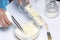 The woman grinds the butter and adds to the dough. Next container with flour and coconut shaving.