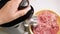 Woman grinds meat on an electric meat grinder top view