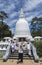 Woman and group of children in uniform on the stairs at white buddhist stupa building located in Nuwara Eliya town