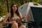 Woman guitarist playing ukulele in campsite in forest trip