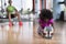 woman in a gym stretching and warming up man in background working with dumbbels