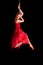 Woman gymnast in red dress on rope on black background