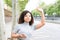 Woman hailing a uber with raised hand while holding a cell phone in the city. Horizontal photograph