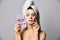 Woman with hair in towel, cosmetic moisturizing cloth mask with closed with pleasure eyes enjoys feeling of natural skin care