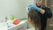 Woman hairdresser colorist at home in the bathroom puts paint on the hair of a young woman, applies paint with a brush