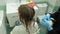 Woman hairdresser colorist at home in the bathroom puts paint on the hair of a young woman, applies paint with a brush