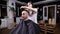 A woman hairdresser completes hair styling for a visitor of a barbershop, a hair stylist uses a gel for styling to shape