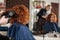 The woman in the hairdresser makes a new hairstyle. Reflection in the mirror blurred