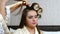 Woman hairdresser put on curlers to long hair woman