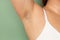 Woman with hairy underarms closeup, free copy space, green background. Raised arm with armpit hair. Female beauty trend