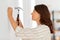 Woman hammering nail to wall at home