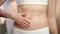 Woman hand applying body cream on abdomen. Woman belly skincare