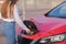 Woman Hand Attaching Power Cable To Environmentally Friendly Zero Emission Electric Car. Woman makes power supply