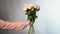 Woman hand in blouse giving pink rise flowers bouquet