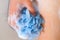 Woman hand with blue foamy sponge washing her body