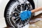 Woman hand with blue microfiber fabric washing wheel modern car or cleaning automobile.