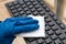 Woman hand in blue protective glove cleans with a disinfectant cloth keyboard surface for prevention coronavirus, bacteria,