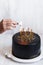 Woman hand burning candles on Black birthday cake