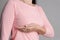 Woman hand checking lumps on her breast for signs of breast cancer on gray background. Healthcare concept