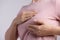 Woman hand checking lumps on her breast for signs of breast cancer on gray background. Healthcare concept