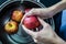 woman hand is cleaning red apple in bucket of water, closed up