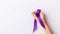 Woman hand closeup holding purple ribbon as symbol of World Cancer Day, closeup. generative ai