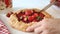 Woman hand cut a strawberry galette tart pie with fresh strawberries