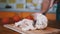 Woman hand cuts cooked chicken fillet on a cutting board with a fork and knife.