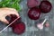 Woman hand cutting roots of cooked peeled beet on the black background