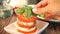 Woman hand decorated with basil leaf herb caprese salad with mozarella cheese, tomatoes and basil