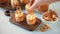 Woman hand decorated homemade whipped cream cheese cupcakes with caramel syrup