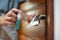 Woman hand disinfecting the door handle by spraying a blue sanitizer from a bottle for Covid-19 Coronavirus prevention