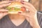 Woman hand eating burger closeup unhealthy junk food concept