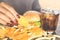 Woman hand eating fast food burger, potato chips,french fries and sweet drink on wooden table