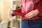 Woman hand fastening belt of red jacket at home