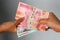 Woman Hand give Indonesian Money Rupiah. Woman hand is holding bunches of Indonesian Rupiah bank notes currency