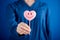 Woman hand giving pink heart shaped lollipop with smile