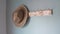 Woman hand grab jacket and straw hat on clothes hanger in living room