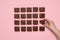 Woman hand grabbing a piece of fudge. Chocolate fudge on pink background top view