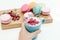 Woman hand hold blue cappuccino cup with roses petals and beauty macarons on wood desk
