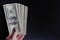 Woman hand hold fan of bills on dark background. Hundred dollars banknotes, pack of money, loan.
