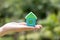 Woman hand hold home model with blur green background Concept for dream home, family fulfillment