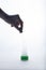 Woman hand hold medicine dropper above laboratory beaker with green liquid and smoke