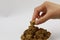 A woman hand hold a piece of brown sugar, cubes rock sugar on a plate, on white background, diabetes